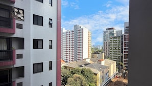 A high-rise building with multiple windows and balconies, surrounded by other buildings and trees. - Vrbo Property (São Paulo)