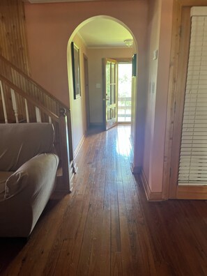 A hallway with wooden flooring, a staircase, and a door leading to an outdoor area. - Lovely 3-bedroom house with AC in charming rural Abbeville.  Quiet country home. (Abbeville)
