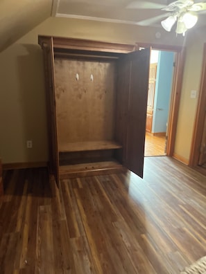 Ein Zimmer mit Holzboden, einer eingebauten Sitzbank und einem Deckenventilator.