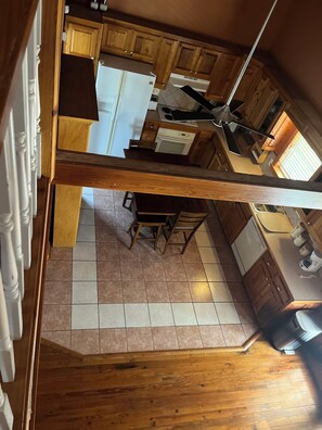 A kitchen with wooden cabinets, a refrigerator, a dishwasher, and a dining area with chairs and a table. - Lovely 3-bedroom house with AC in charming rural Abbeville.  Quiet country home. (Abbeville)