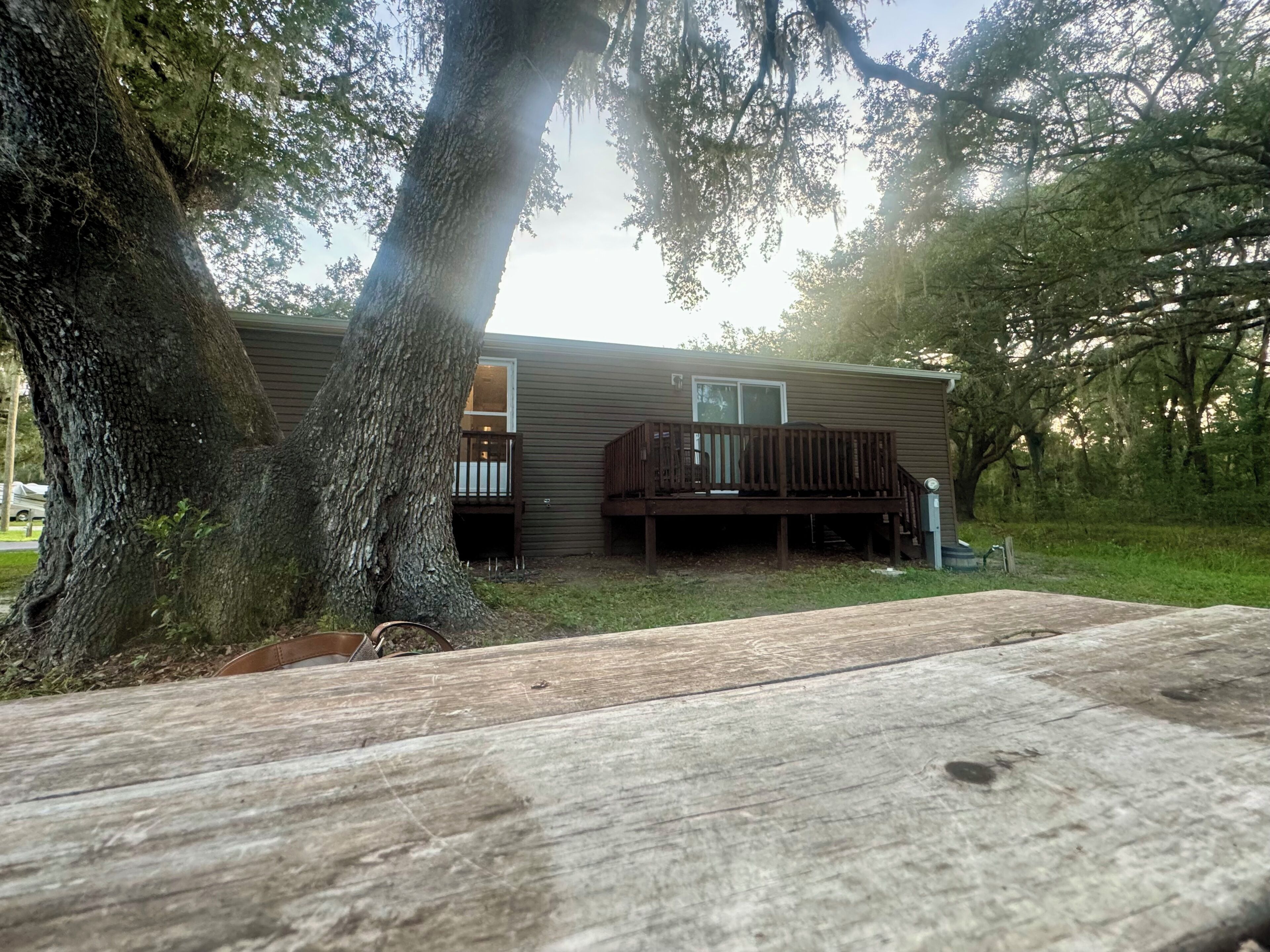 A single-story house with a deck, surrounded by trees.
