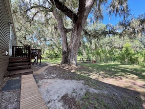 A wooden deck leading to a covered area with a picnic table and benches.