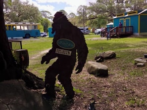 A person in a costume walking on a grassy area with rocks and a bus in the background.