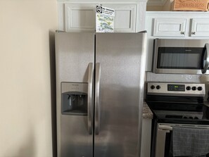 Ein Edelstahl-Kühlschrank mit Wasserspender, Mikrowelle und Backofen.