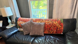 A black leather sofa with a colorful patterned throw blanket and two pillows. - 2-bedroom condo in welcoming Plaistow close to beaches, mountains, and Boston (Plaistow)