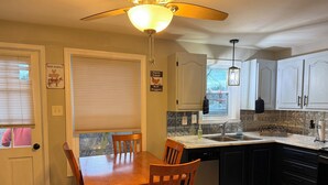 A kitchen with a dining table, chairs, a ceiling fan, a window, and a sink. - 2-bedroom condo in welcoming Plaistow close to beaches, mountains, and Boston (Plaistow)