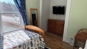 A bedroom with a bed, dresser, TV, and a view of the outdoors. - 2-bedroom condo in welcoming Plaistow close to beaches, mountains, and Boston (Plaistow)