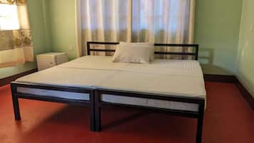 A single bed with a wooden frame and white bedding in a room with green walls and a red carpet.