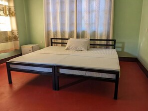 A single bed with a wooden frame and white bedding in a room with green walls and a red carpet. - Kilimanjaro Campsite (Shirimatunda)