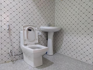 A bathroom with a toilet and a pedestal sink against a tiled wall. - Kilimanjaro Campsite (Shirimatunda)