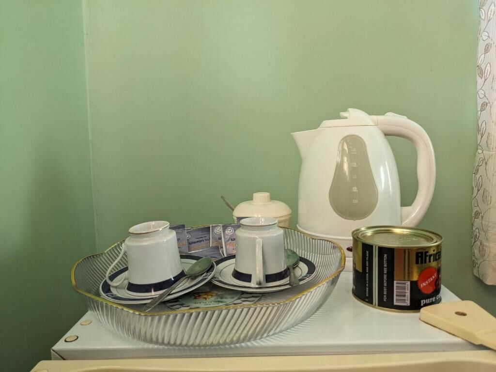 A kitchen counter with a coffee maker, a kettle, a can of food, and a cutting board.