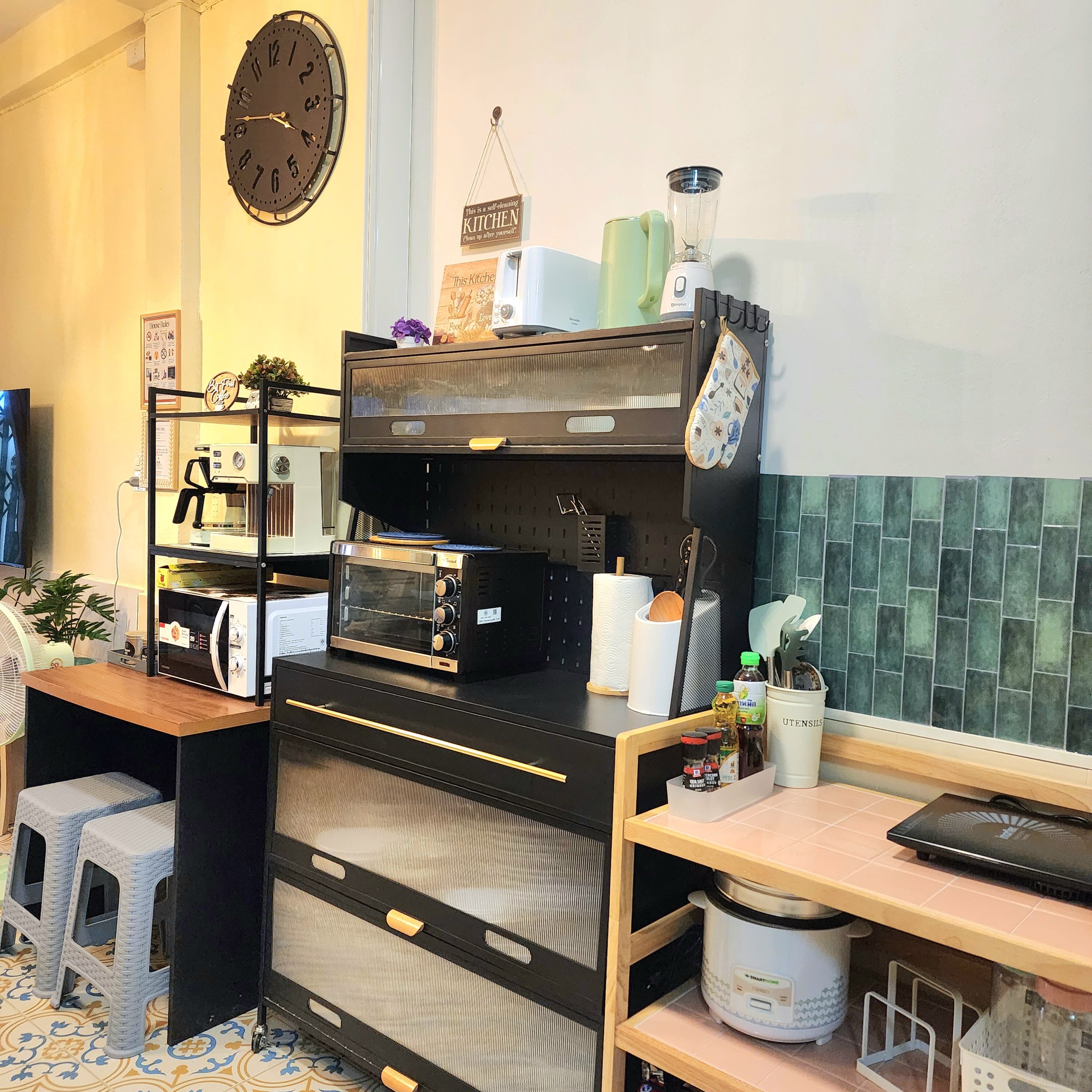 Une cuisine avec une horloge, un grille-pain, un mixeur et un ordinateur portable posés sur un plan de travail.