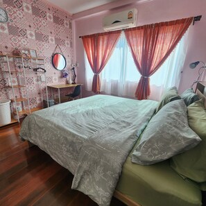 Une chambre à coucher comprenant un lit, un bureau, une chaise, un miroir et un climatiseur fixé au mur.