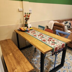 A dining area with a wooden table, benches, a floral table runner, and a vase with flowers. - 3BR Local Bangkok Stay [10 Min Walk to BTS & Sathorn Pier ] • Easy City Access (Sathon)