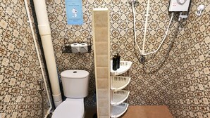 Ein kleines Badezimmer mit Toilette, Dusche und einem Händetrockner.