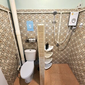 Une petite salle de bain comprenant des toilettes, une douche et un sèche-mains.