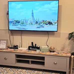 Ein an der Wand befestigter Fernseher zeigt eine Stadtansicht mit einem markanten Turm.