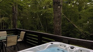 Ein Whirlpool auf einer Terrasse, umgeben von Bäumen.