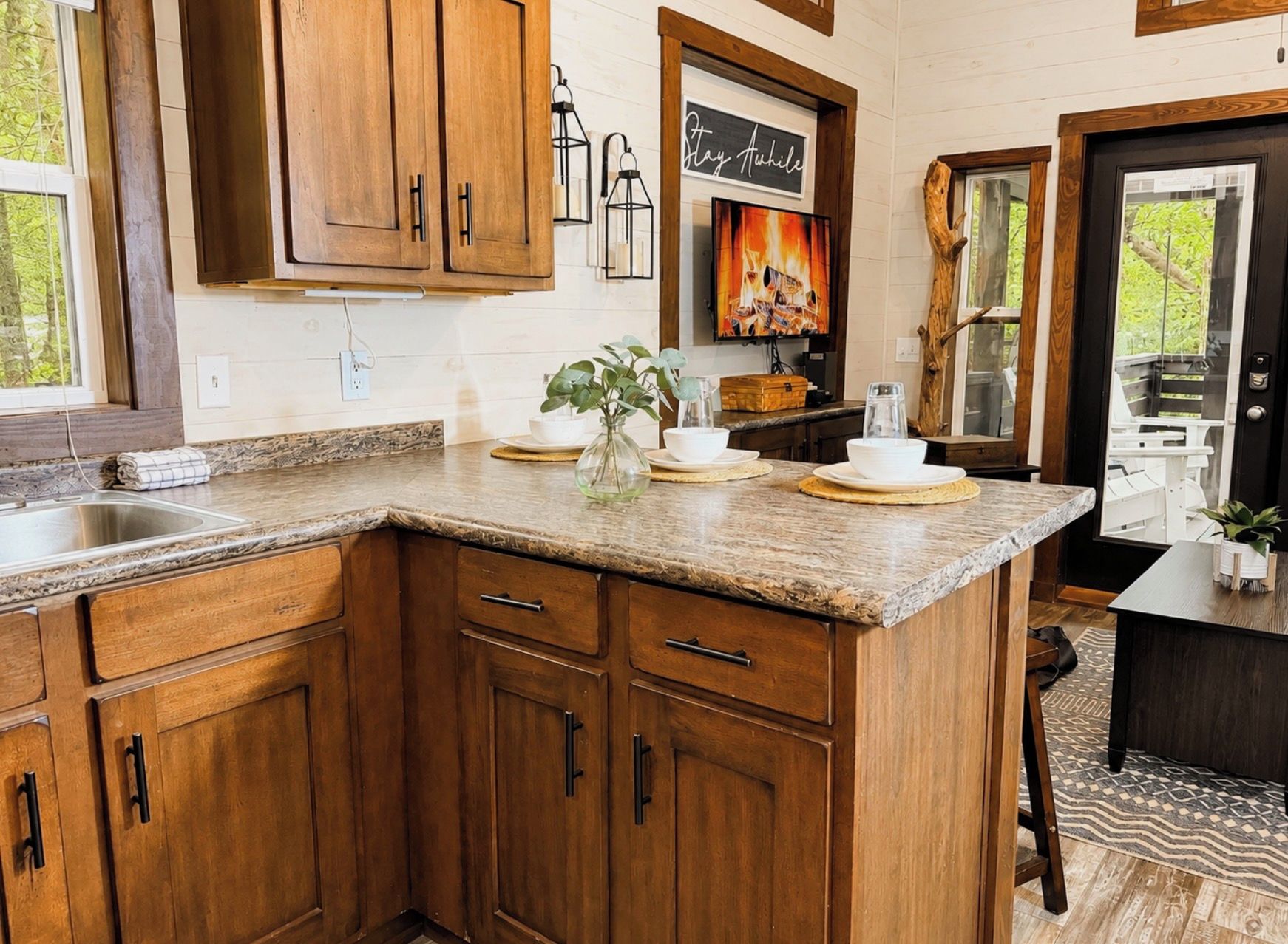 Una cocina con armarios de madera, encimera de granito, un fregadero y una zona de comedor con mesa y sillas.