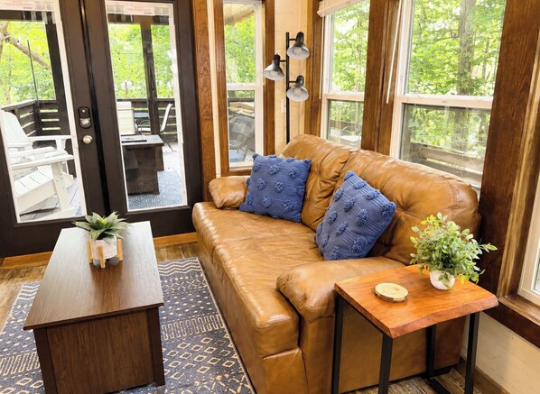 A cozy room with a leather sofa, a wooden coffee table, and a small side table with a plant.