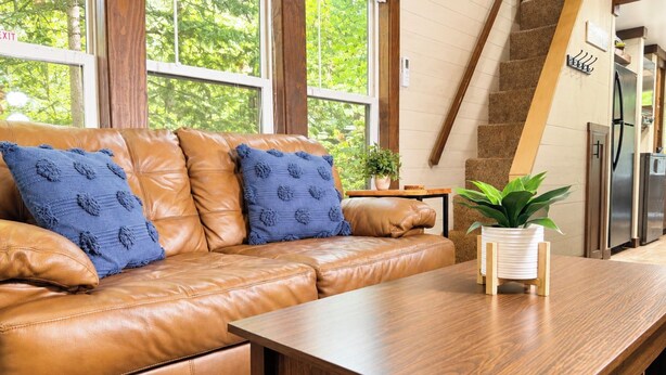 A modern living room with a leather sofa, a wooden coffee table, and a staircase leading to an upper level.