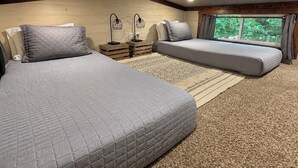 A bedroom with two beds, a window, and a ceiling light.