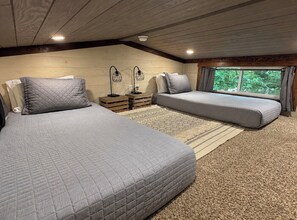 A bedroom with two beds, a window, and a ceiling light.