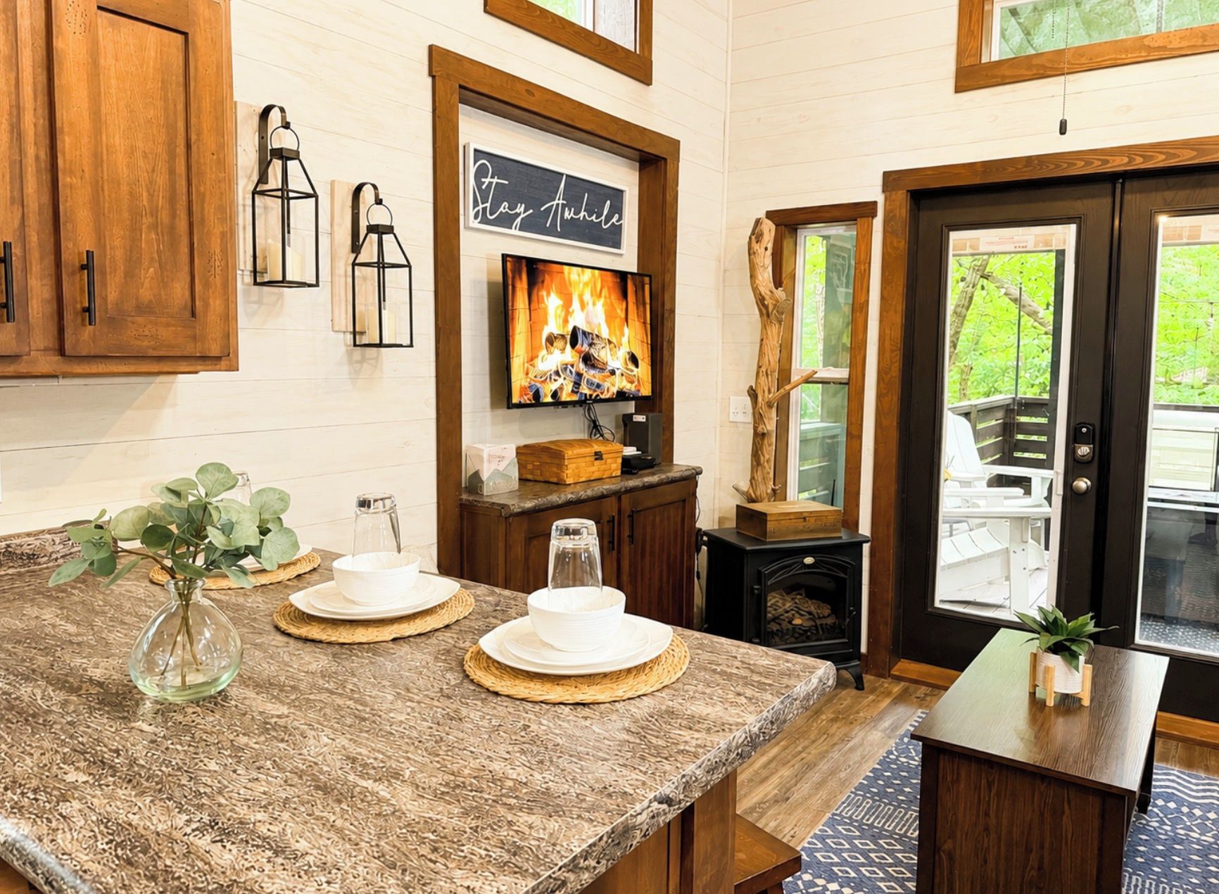 A kitchen with wooden cabinets, a stone countertop, a fireplace, and a television.