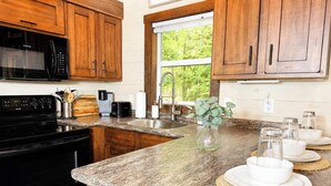 A kitchen with wooden cabinets, a black microwave, a stove, and a granite countertop.