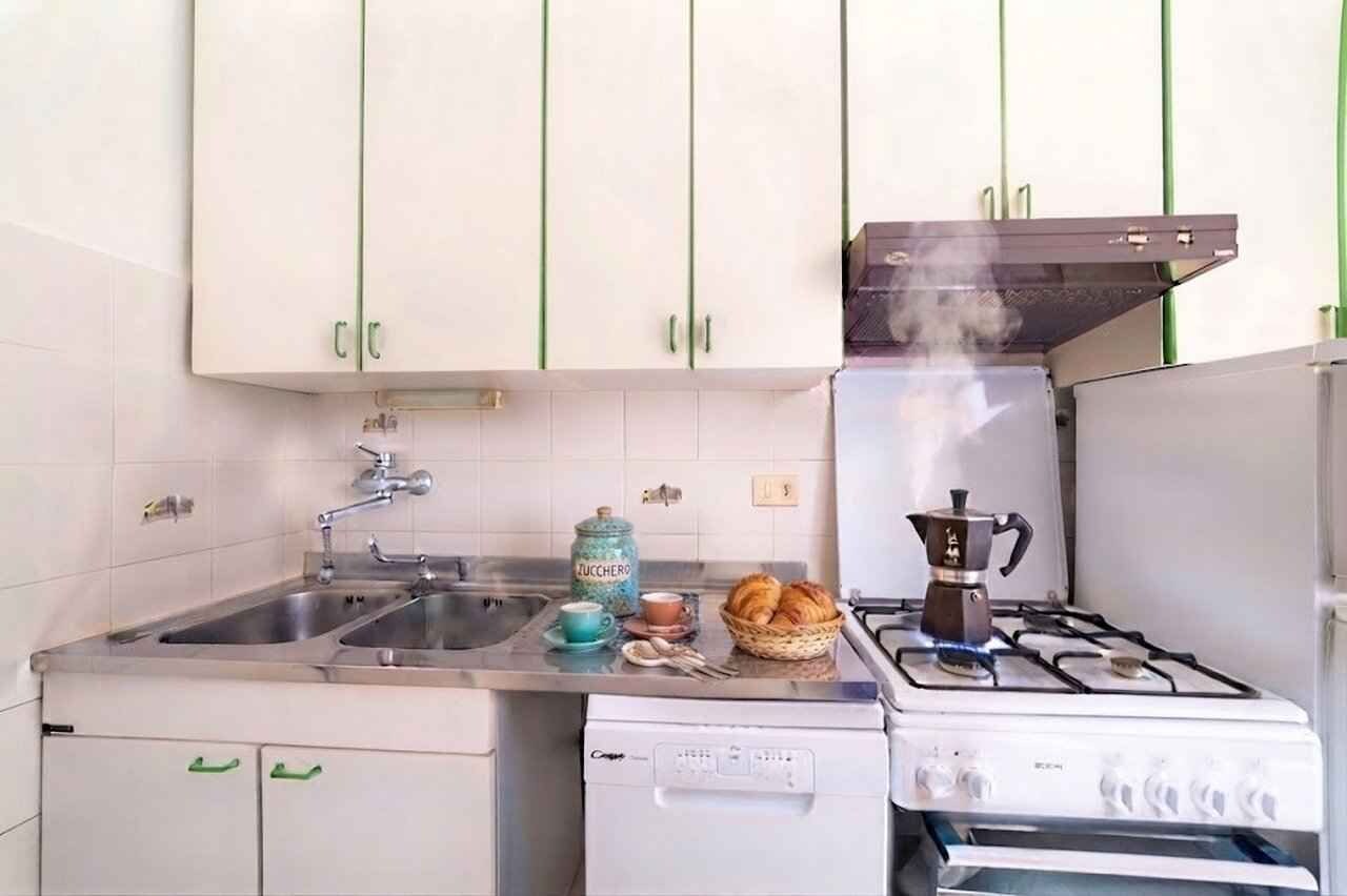 A compact kitchen with a gas stove, a coffee maker, and a sink.
