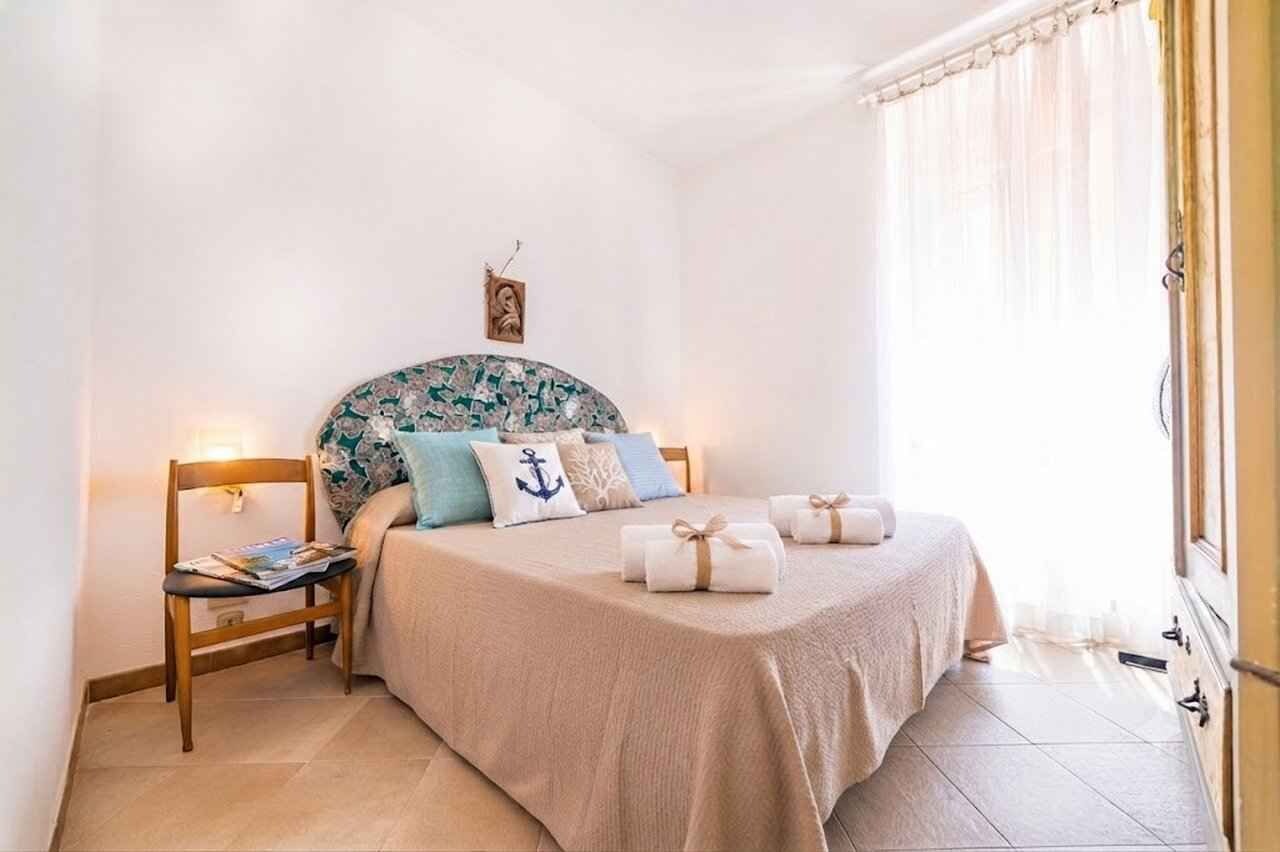 A bedroom with a bed, bedside table, and a window with curtains.