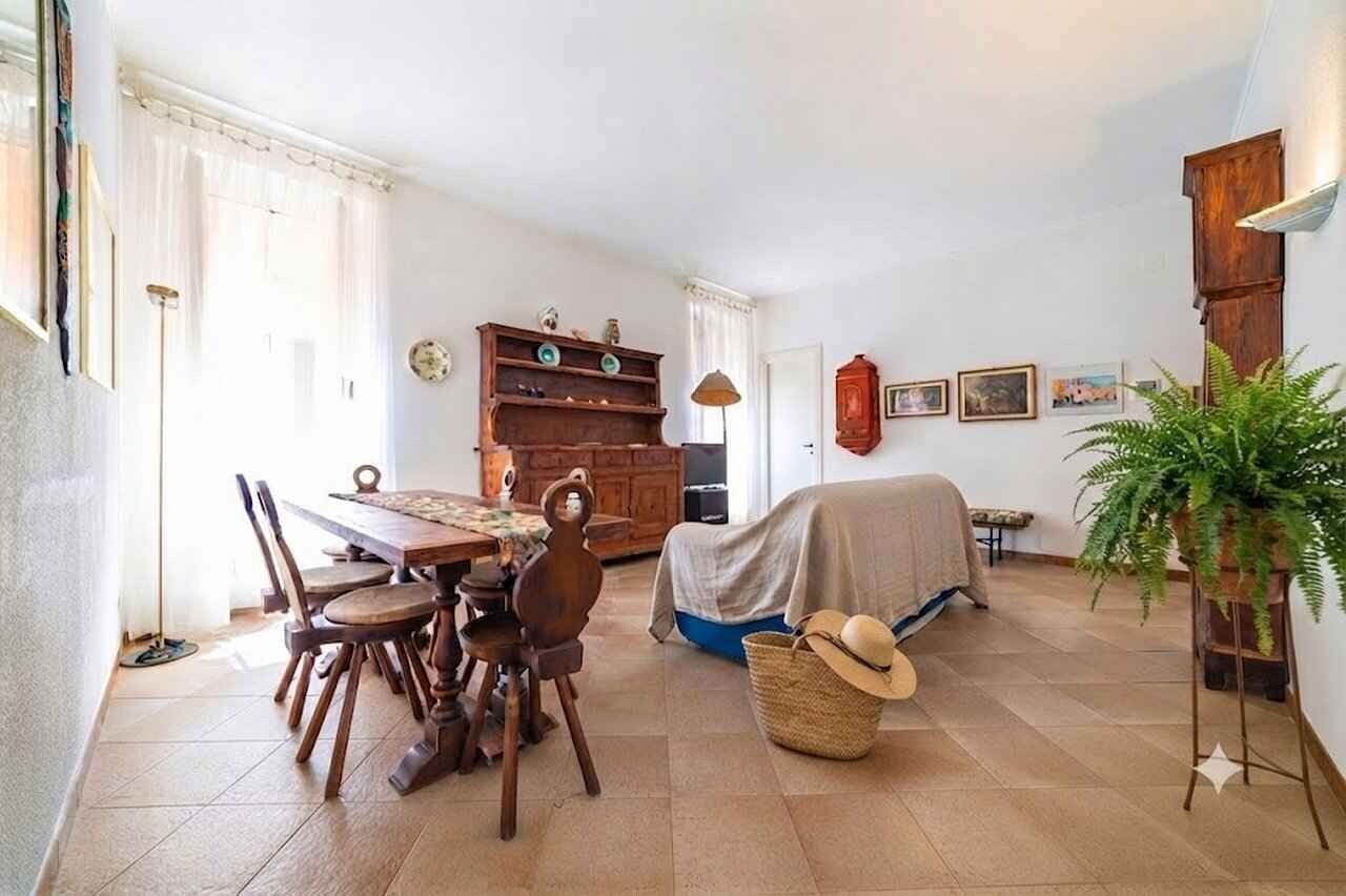 A dining area with a wooden table and chairs, a kitchen with a wooden cabinet, and a bed with a blanket.