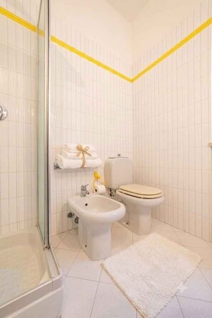 A bathroom with a shower, a bidet, a toilet, and a sink. - Holiday flat with washing machine (Imperia)