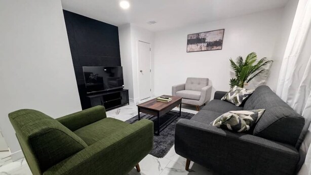 Uma sala de estar moderna com um sofá, poltrona e televisão de tela plana.