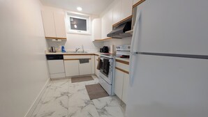 Cozinha compacta com armários brancos, forno embutido, micro-ondas e geladeira.