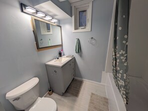 Ein Badezimmer mit Toilette, Waschbecken, Spiegel und Duschvorhang.