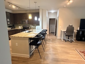 A modern kitchen with a central island, bar stools, and pendant lighting. - 2-bedroom 2-full bath apartment in adorable Houston Energy Corrido area (Houston)