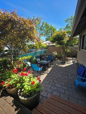 A patio area with outdoor furniture, potted plants, and a wooden bench.