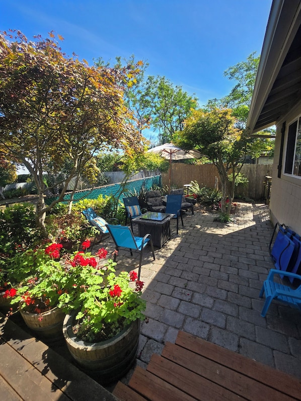 A patio area with outdoor furniture, potted plants, and a wooden bench.