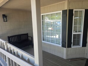 A covered porch with a bench, a large window with blinds, and a small lantern.