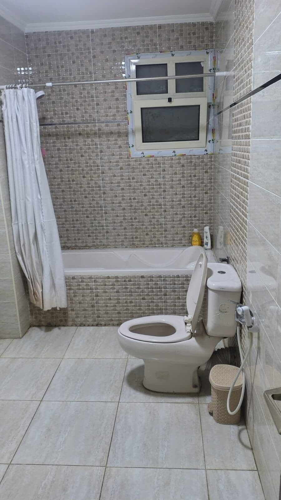 A bathroom with a toilet, a bathtub, and a shower curtain.