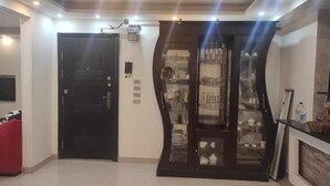 A room with a black door, a glass-fronted cabinet with dishes, and a red chair. - Luxrious Comfy Apartments East Cairo (Cairo Governorate)
