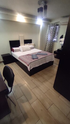Una habitación de hotel con una cama, mesitas de noche, un escritorio y una silla.