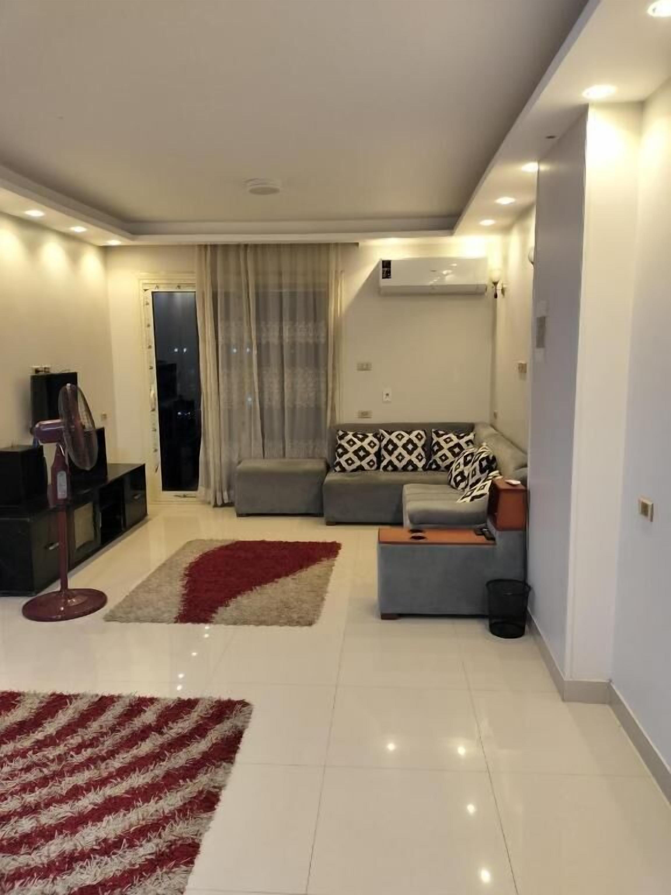 A modern living room with a sofa, a coffee table, and a red and white rug.