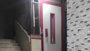 A staircase leading to a door with a red frame, a wall with a textured pattern, and a metal railing. - Luxrious Comfy Apartments East Cairo (Cairo Governorate)