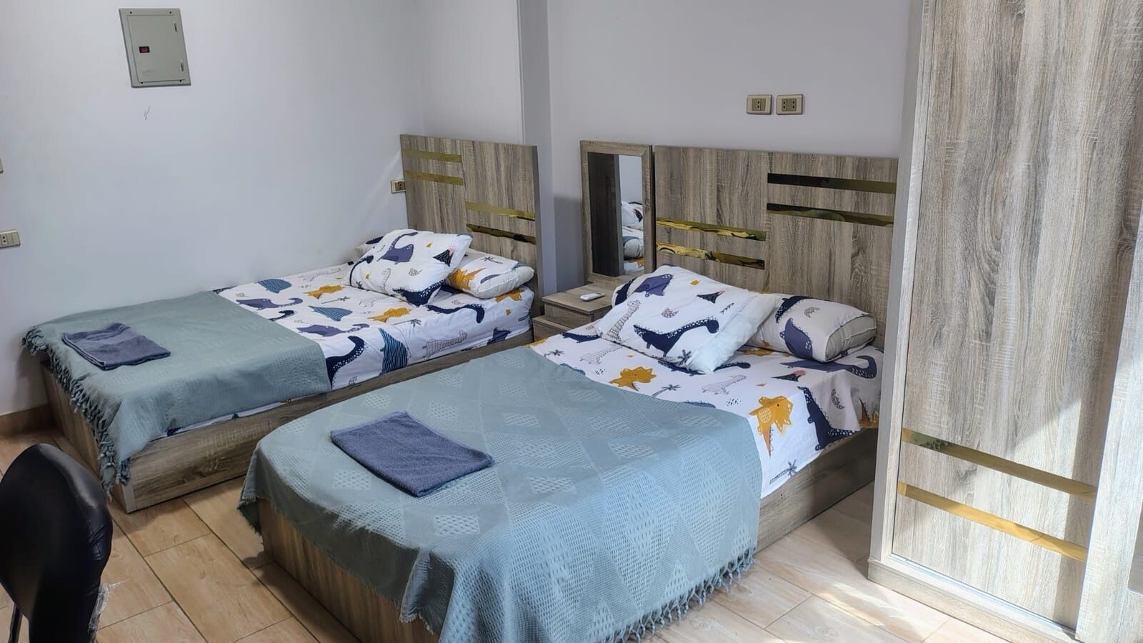 Ein Zimmer mit zwei Einzelbetten, einem Holzkopfende, einem kleinen Tisch und einem Stuhl.