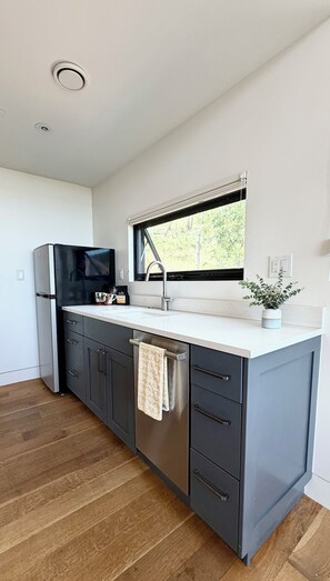 Eine moderne Küche mit integriertem Kühlschrank, Spüle aus Edelstahl und einem Fenster über der Arbeitsfläche.