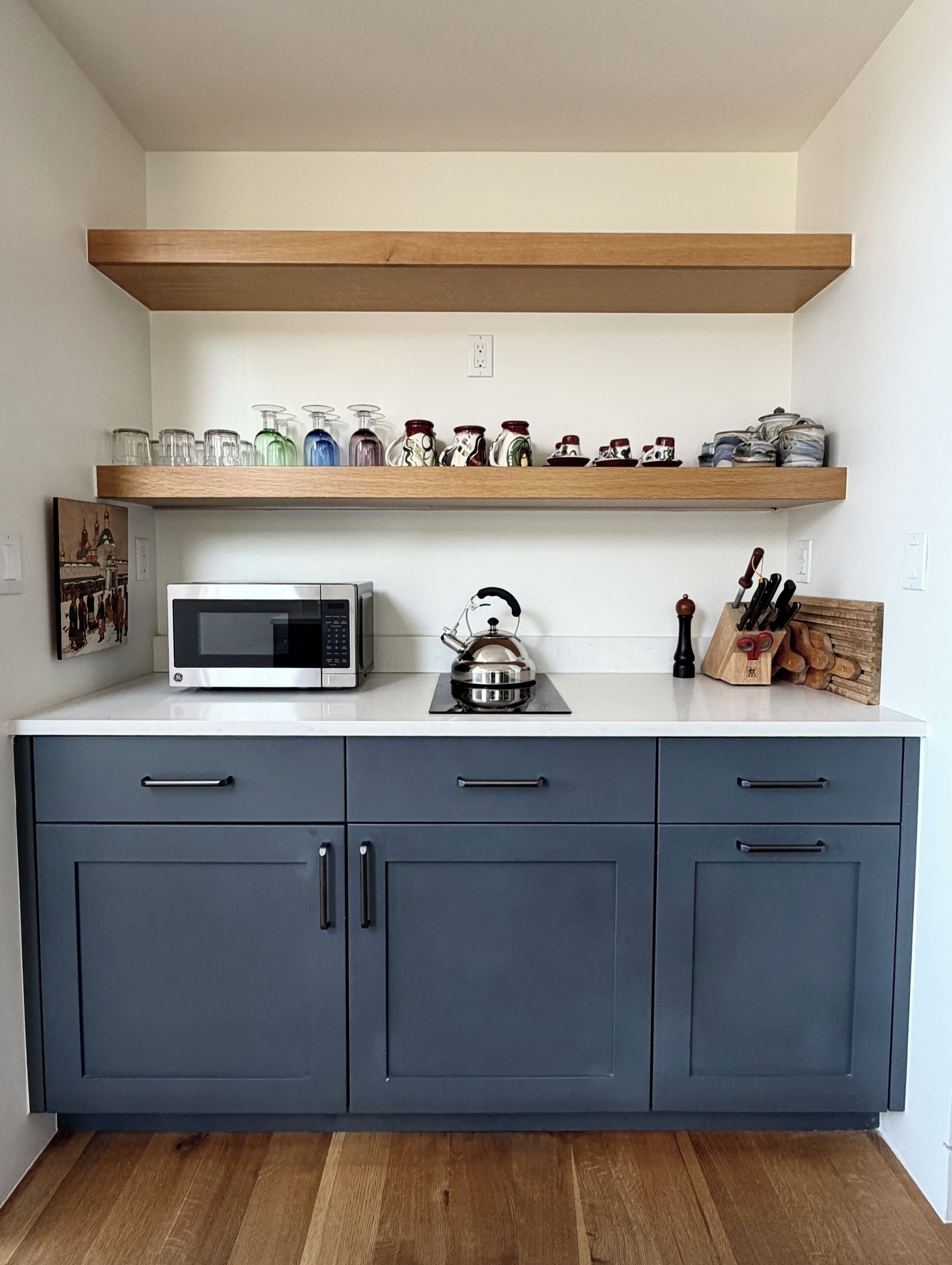 A kitchen with a microwave, kettle, and knife block on the countertop.