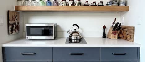 A kitchen with a microwave, kettle, and knife block on the countertop.