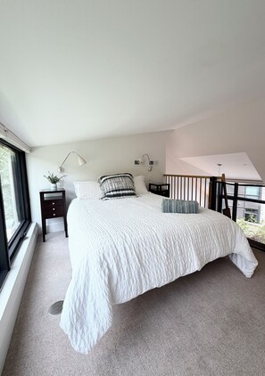 Quarto com uma cama grande, duas mesas de cabeceira, uma janela e vista para o exterior.